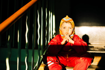Deadpan shoot with a boy wearing red clothes. Kid is sitting on the stairs
