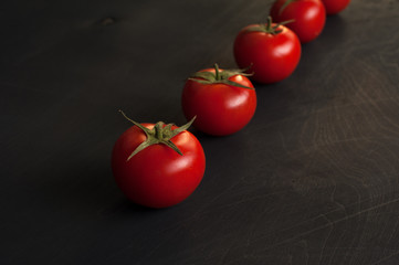 Row of cherry tomatoes on dark background. Vegetarian or vegan menu design. Place for text.