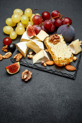 Camembert cheese with honey, figs, walnuts on stone board