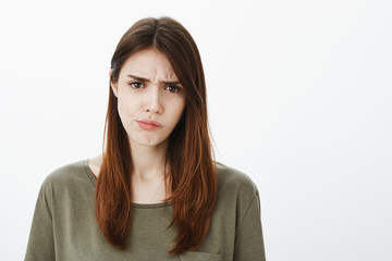 Attractive smart female coworker in casual clothes, frowning and expressing displeasure and...