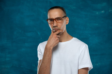 Portrait of young stylish hipster guy wearing glasses looking at the camera on blue background