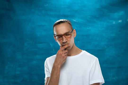 Portrait of young stylish hipster guy wearing glasses looking at the camera on blue background