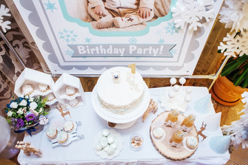 festive table with cake, cupcakes, marshmallow, flowers and juices for children