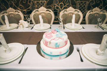 cake with mastic decorated with drawings of  stroller and a horse stands on a table in the cafe