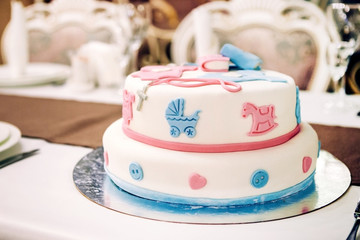 idea of decorating a cake with mastic and with elements of a stroller, buttons, a horse and ribbons for birthday