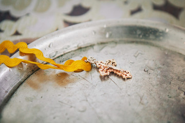 golden cross with a rope lays on a metal plate