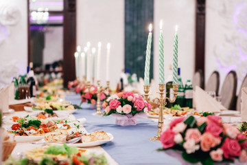 table with bouquets of roses, flowers and snacks for guests
