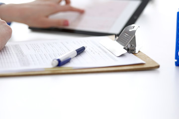 Woman doctor using tablet computer while sitting at the desk in hospital closeup. Cardiologist checks heart diagrams with tablet pc. Healthcare, insurance and smart technology in medicine concept