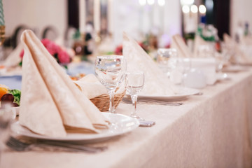 table for guests covered with a tablecloth and decorated with napkins, cutlery, glasses and food