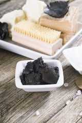massage spa setting: mud, shea butter, organic soaps, bath salt, brush on old wood table background