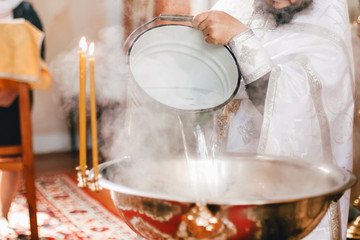 priest prepares water for the ceremony of baptism