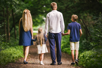 family are walking on the path in the park in warm weather