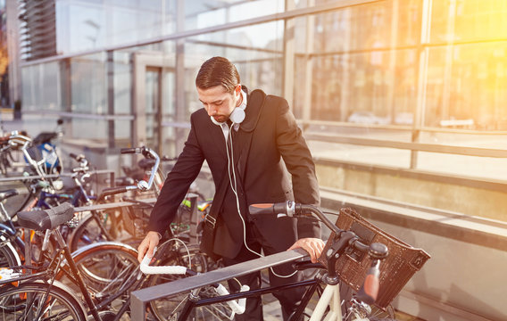 Business Mann stellt Fahrrad an Fahrradständer