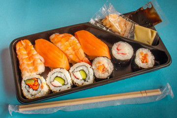 Take away sushi box with salmon and shrimp nigiri and hosamaki with ginger and wasabi.