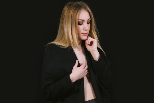     Sexy lady in nylons and long coat undressing, dark background. Elegant woman wearing black sensual lingerie. Erotic noir concept. 