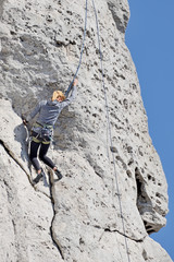 A woman climbing the rocks. - obrazy, fototapety, plakaty