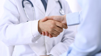 Male doctor and woman patient shaking hands. Partnership in medicine, trust and medical ethics concept