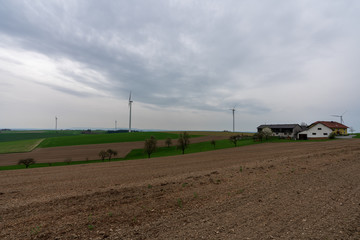 Fototapeta na wymiar Windräder in Hügellandschaft mit Bauernhof