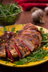 Grilled chicken breast with green salad from arugula and vegetables on a yellow plate. Wooden rustic background. Top view