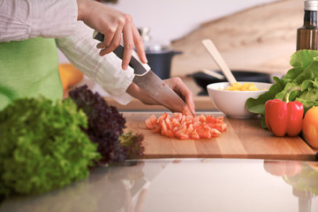 Close Up of human hands cooking vegetable salad in kitchen on the glass table with reflection. Healthy meal, and vegetarian food concept