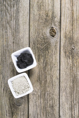 gray cosmetic clay powder and black mud on old wood texture