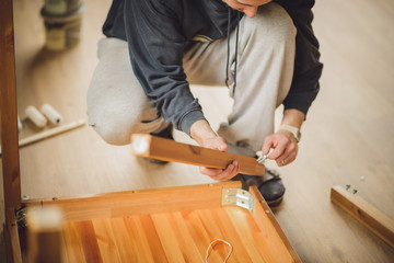 man screws the legs to a wooden table