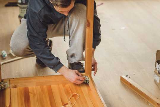 man screws the legs to a wooden table