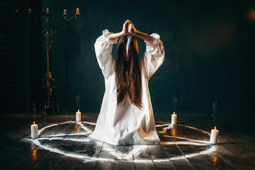 Woman with knife sitting in pentagram circle