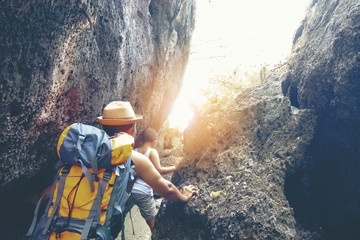 Brother and brother are climbing rock mountain with background of sunset on the beach.