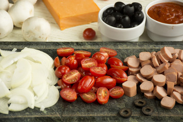 Ingredients for Italian pizza with cheddar cheese, mushrooms, black olives and sausage on white wooden background 