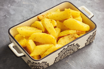 Baked potatoes with garlic and spices on wooden background.