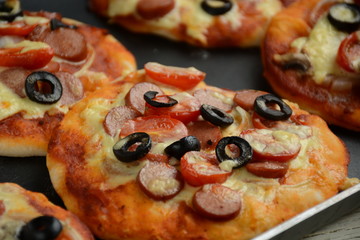 Italian pizza with cheddar cheese, mushrooms, black olives and sausage on white wooden background 