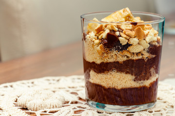 Delicious dessert with banana and biscuits chocolate pudding in glass cup on table