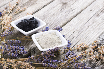 cosmetic clay powder and mud with dried lavender flowers on old weathered wooden table background