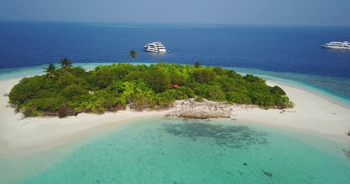 Aerial view of a desert island with a clear and transparent sea and a pristine beach. Concept of: holidays, maldives, dream landscapes.