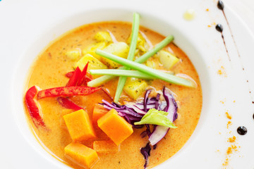Coconut curry soup with pumpkin, celery, bell pepper, cabbage on white rustic table