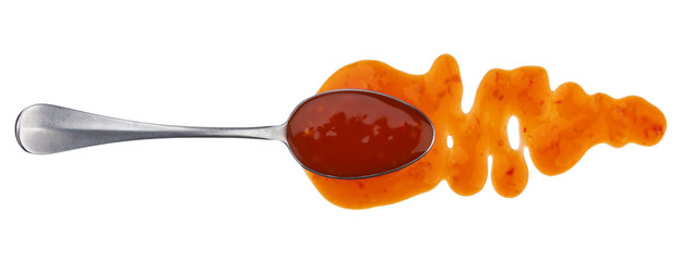 Splashes and spilled sweet and sour sauce with spoon isolated on white background. Top view