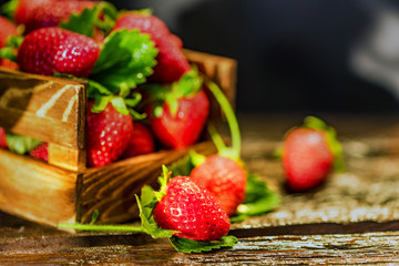 Fresh strawberries with leaves in wooden box close
