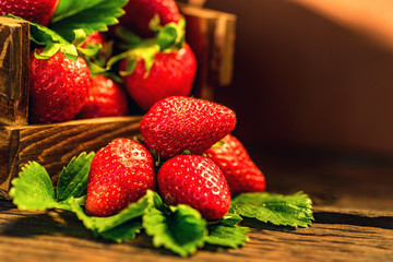 Fresh strawberries with leaves in wooden box close