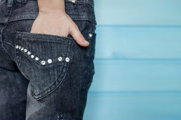 The hand in the back pouch of jeans, trimmed with rhinestones