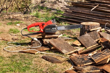 Electric saws and chainsaw. Electric saw chain on the background of sawn timber. The concept of processing wood to produce fuel.