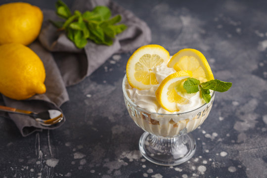 Lemon dessert. English lemon trifle, cheesecake, whipped cream, parfait. Fruit mousse in glass on a dark background.
