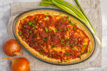 Traditional French onion pie. Quiche lorraine with onion, cheese and eggs in a glass oven dish, top view