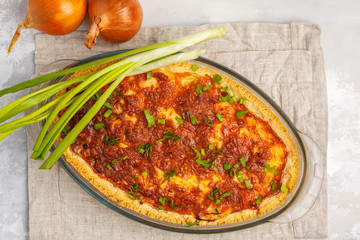 Traditional French onion pie. Quiche lorraine with onion, cheese and eggs in a glass oven dish, top view
