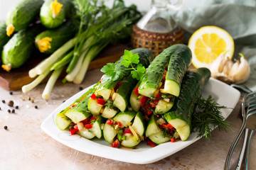 Korean traditional food Kimchi (Cucumber). Marinated cucumbers with vegetable filling (sweet pepper, garlic, onion, greens, tomato paste) on a stone or slate background.