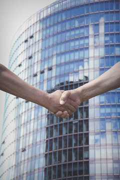 Male hands handhsake with business building on background