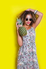Fashion summer portrait afro american girl in sunglasses and pineapple over yellow background