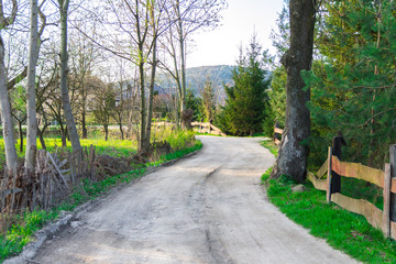 Rural dirt road, beautiful village in the summer, the road under the old fallen fence