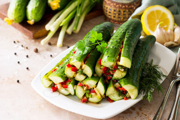 Kimchi of the Korean pickle cucumber. Marinated cucumbers with vegetable filling (sweet pepper, garlic, onion, greens, tomato paste) on a stone or slate background.