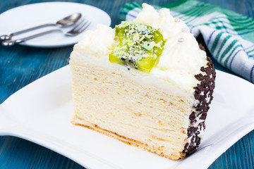 Piece of homemade cake with kiwi and whipped cream